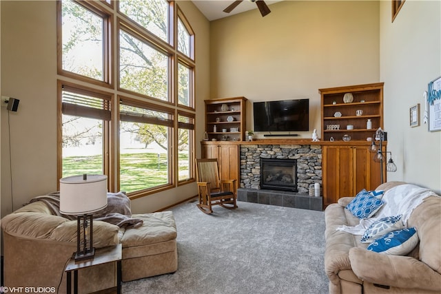 carpeted living room featuring a high ceiling, ceiling fan, and a fireplace