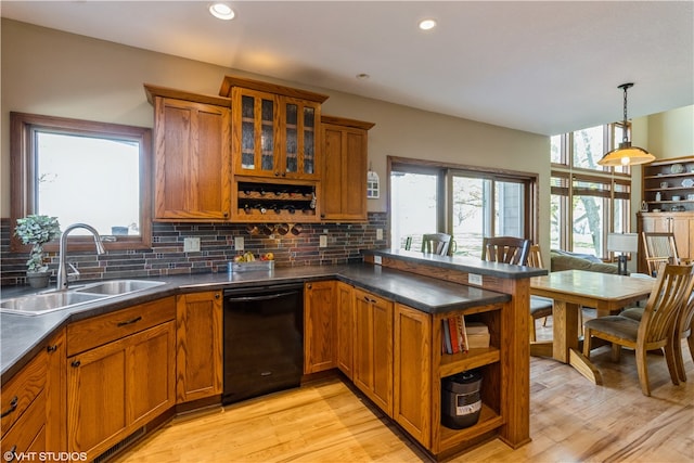 kitchen featuring sink, hanging light fixtures, dishwasher, backsplash, and light wood-type flooring