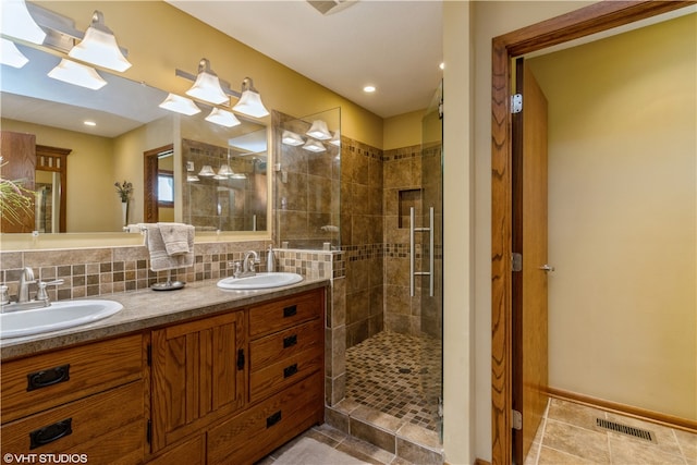 bathroom featuring double sink, a shower with shower door, tile flooring, oversized vanity, and tasteful backsplash