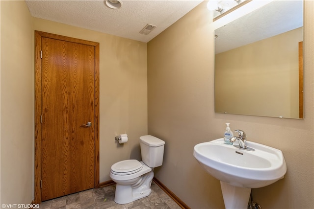 bathroom featuring toilet, tile floors, a textured ceiling, and sink