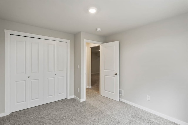 unfurnished bedroom with light colored carpet and a closet