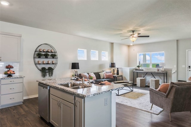 kitchen featuring sink, a center island with sink, dark hardwood / wood-style flooring, dishwasher, and light stone countertops