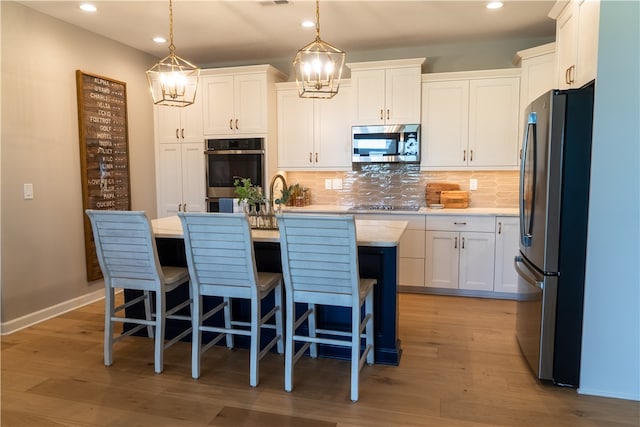 kitchen with a notable chandelier, appliances with stainless steel finishes, hanging light fixtures, and white cabinetry