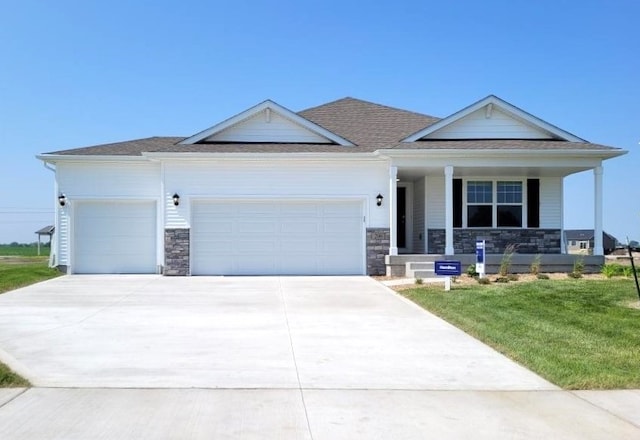 view of front of home with concrete driveway, a front yard, covered porch, stone siding, and an attached garage