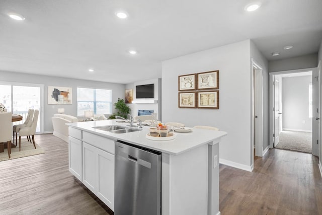 kitchen featuring hardwood / wood-style floors, a center island with sink, white cabinets, stainless steel dishwasher, and sink