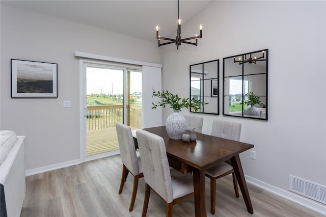 dining space with a chandelier, light hardwood / wood-style floors, and vaulted ceiling