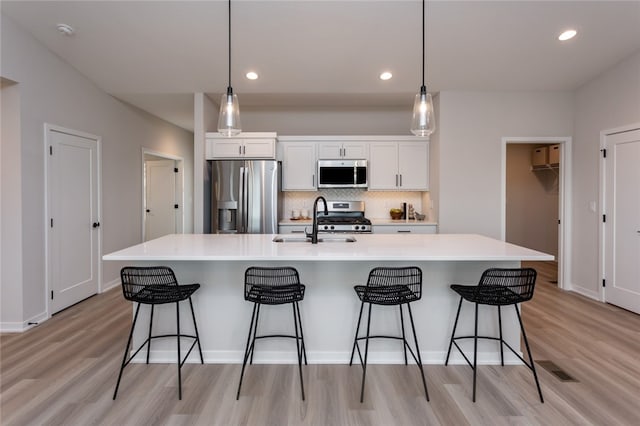 kitchen featuring hanging light fixtures, white cabinetry, sink, and appliances with stainless steel finishes