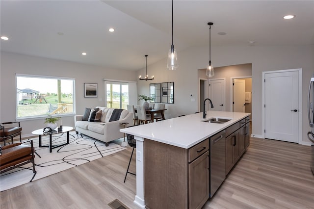 kitchen with stainless steel dishwasher, vaulted ceiling, sink, light hardwood / wood-style flooring, and a chandelier