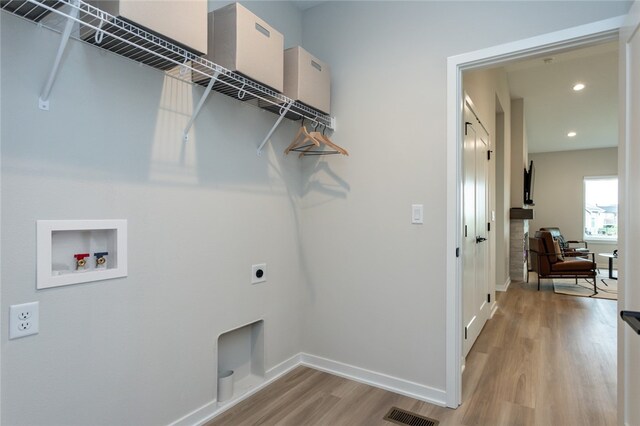 clothes washing area featuring electric dryer hookup, washer hookup, and light wood-type flooring