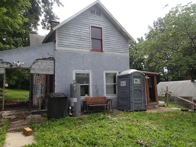 rear view of property featuring a yard, an outdoor structure, and gas water heater