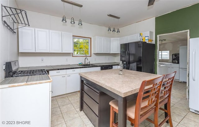 kitchen with decorative light fixtures, sink, white cabinets, a center island, and black appliances