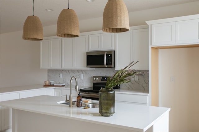 kitchen with hanging light fixtures, a kitchen island with sink, sink, white cabinets, and tasteful backsplash