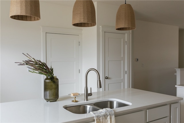 kitchen featuring hanging light fixtures, white cabinets, and sink