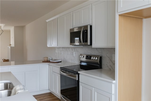 kitchen featuring backsplash, wood-type flooring, appliances with stainless steel finishes, and white cabinetry