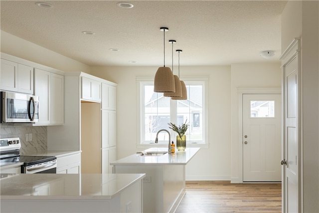 kitchen featuring hanging light fixtures, appliances with stainless steel finishes, sink, light hardwood / wood-style flooring, and tasteful backsplash