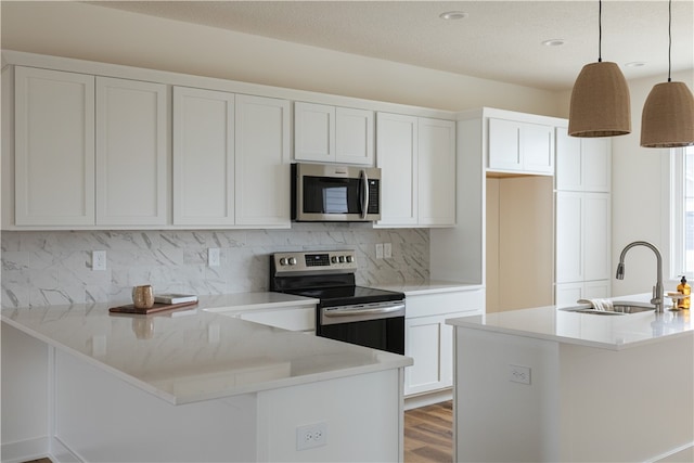 kitchen with white cabinets, wood-type flooring, hanging light fixtures, and appliances with stainless steel finishes