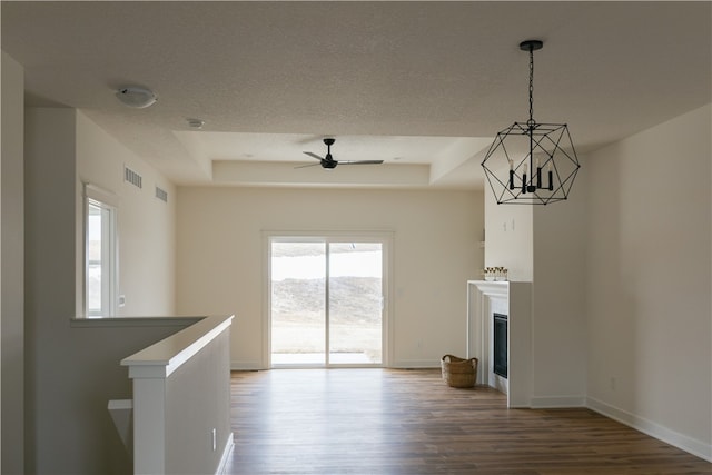 unfurnished living room featuring dark hardwood / wood-style flooring, a healthy amount of sunlight, and a tray ceiling