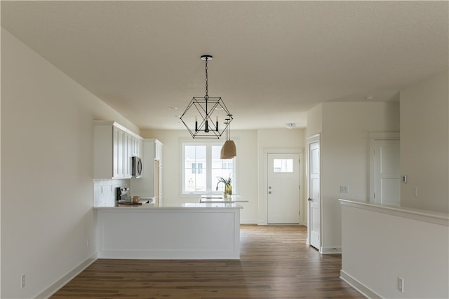 kitchen with range, white cabinetry, dark hardwood / wood-style floors, an inviting chandelier, and pendant lighting