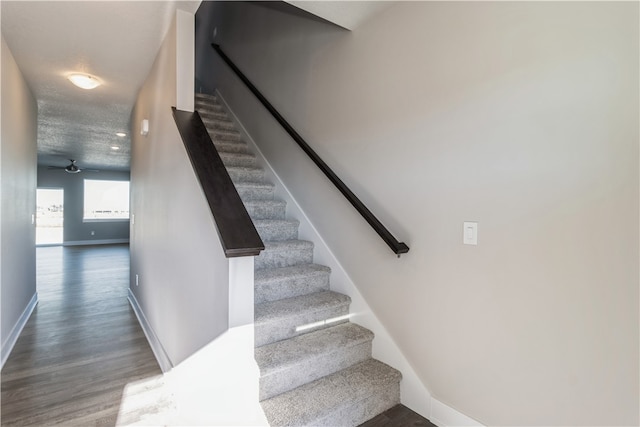 stairs featuring a textured ceiling, wood-type flooring, and ceiling fan