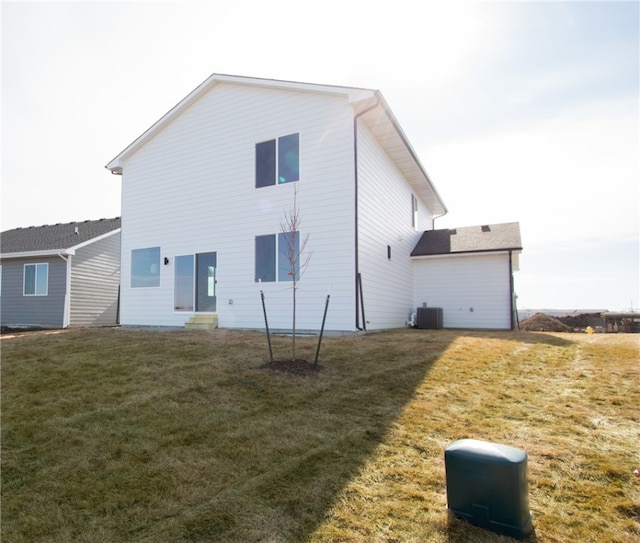 rear view of house featuring central air condition unit and a lawn