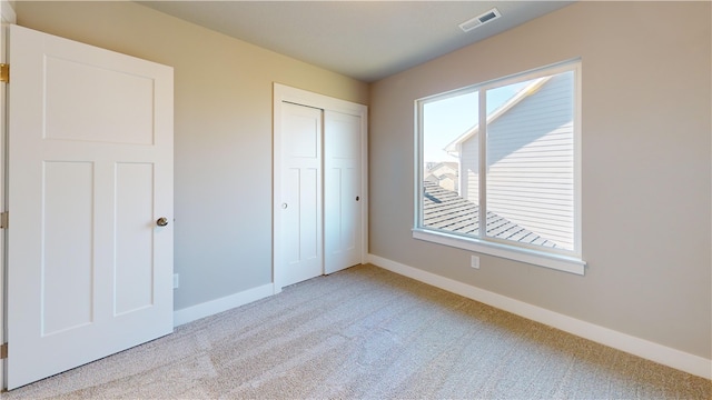 unfurnished bedroom featuring a closet and light colored carpet