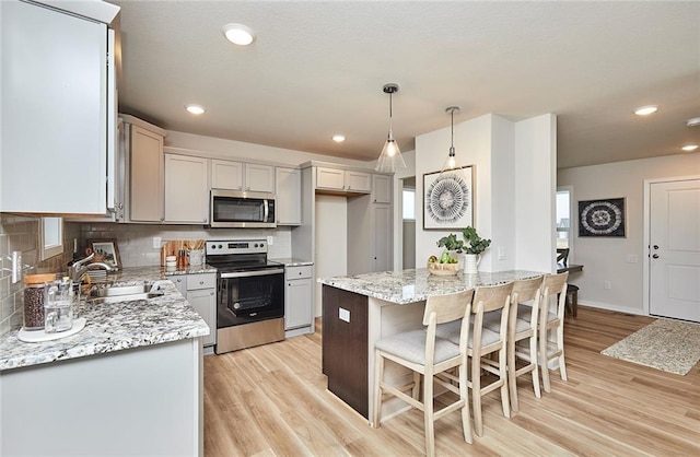 kitchen with pendant lighting, sink, decorative backsplash, a kitchen island, and stainless steel appliances