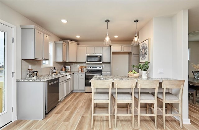 kitchen featuring light stone countertops, sink, stainless steel appliances, decorative light fixtures, and decorative backsplash