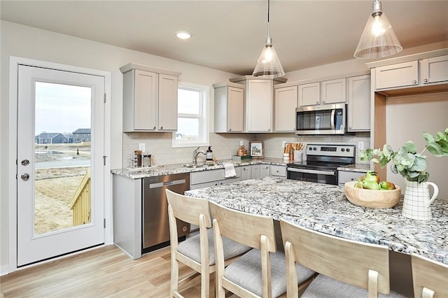 kitchen with decorative backsplash, light stone countertops, stainless steel appliances, and decorative light fixtures