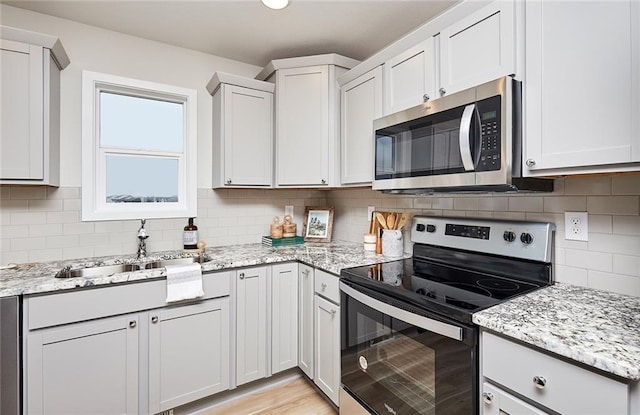 kitchen with backsplash, sink, white cabinets, and appliances with stainless steel finishes