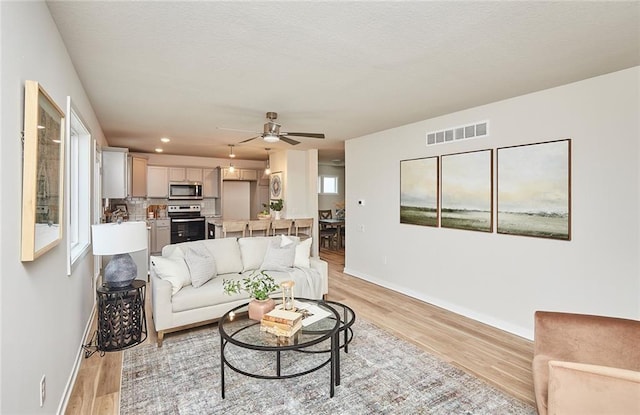 living room with light hardwood / wood-style flooring and ceiling fan