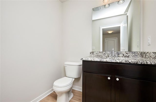 bathroom with hardwood / wood-style flooring, vanity, and toilet