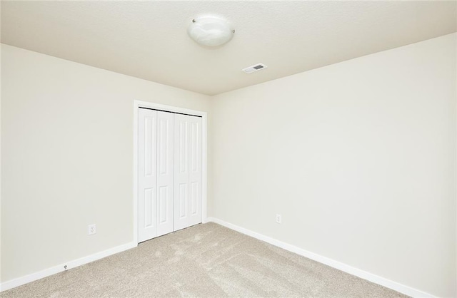 unfurnished bedroom with light colored carpet and a closet