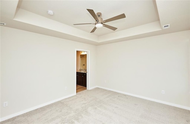 carpeted empty room with a tray ceiling and ceiling fan