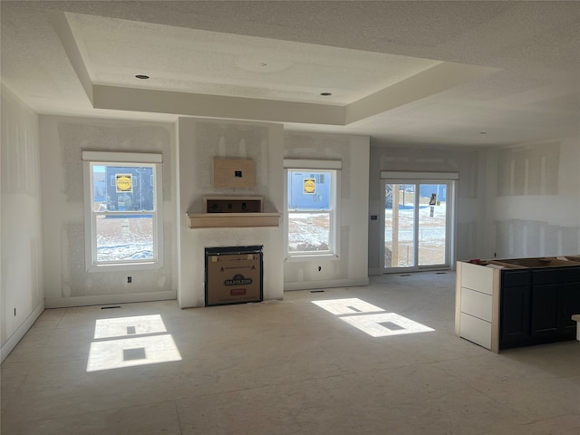 unfurnished living room featuring a textured ceiling, a large fireplace, and a raised ceiling