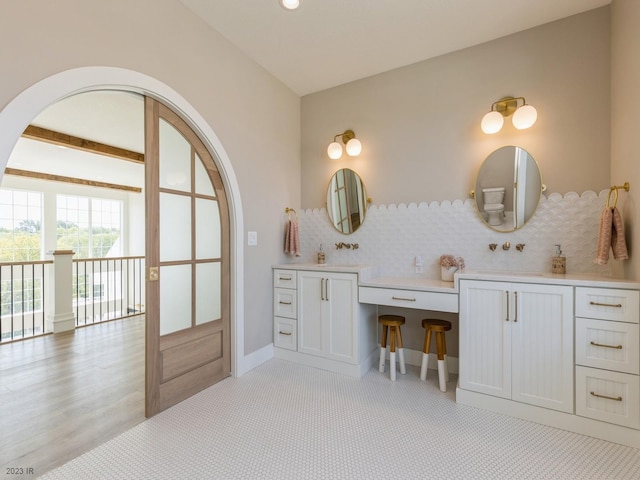 bathroom with hardwood / wood-style floors, backsplash, beamed ceiling, and vanity