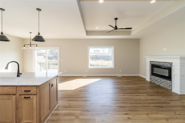 kitchen featuring wood-type flooring, ceiling fan, hanging light fixtures, and sink