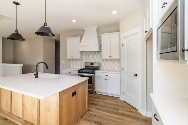 kitchen with stainless steel appliances, white cabinetry, a center island with sink, and sink