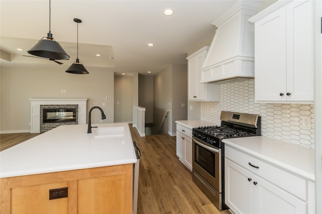 kitchen featuring sink, white cabinetry, gas range, and premium range hood