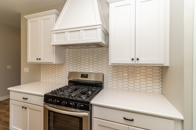 kitchen with decorative backsplash, white cabinets, gas range, custom exhaust hood, and hardwood / wood-style floors