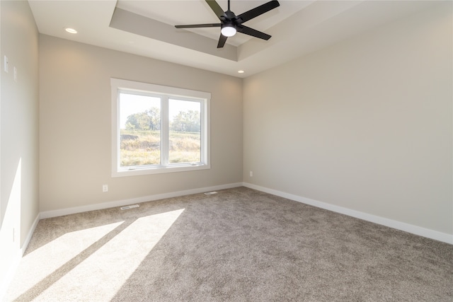 unfurnished room with ceiling fan, a tray ceiling, and carpet flooring