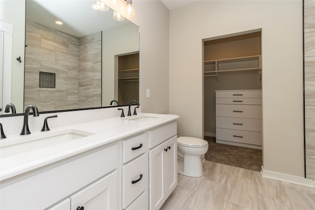 bathroom featuring a tile shower, vanity, and toilet