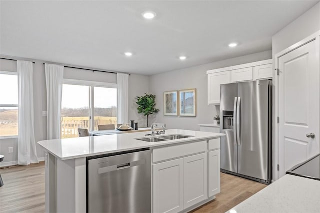 kitchen with sink, white cabinetry, light wood-type flooring, a center island with sink, and appliances with stainless steel finishes