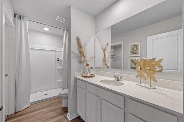 bathroom with hardwood / wood-style floors, toilet, curtained shower, and vanity