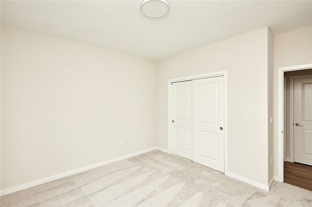 unfurnished bedroom with light colored carpet, a textured ceiling, and a closet