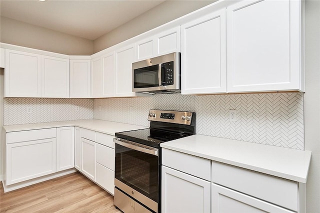 kitchen with appliances with stainless steel finishes, light wood-type flooring, tasteful backsplash, and white cabinetry