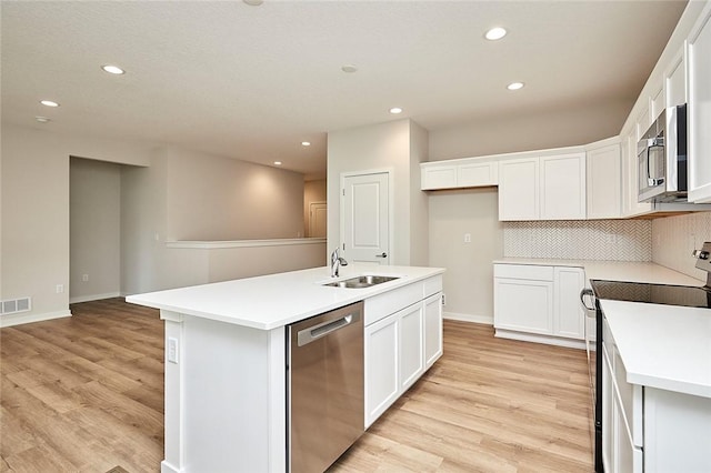 kitchen with white cabinets, appliances with stainless steel finishes, a center island with sink, and sink