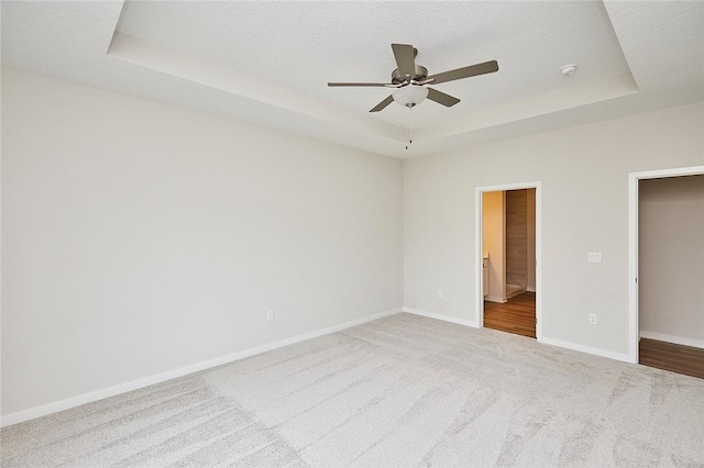 unfurnished bedroom with connected bathroom, ceiling fan, a raised ceiling, carpet floors, and a textured ceiling