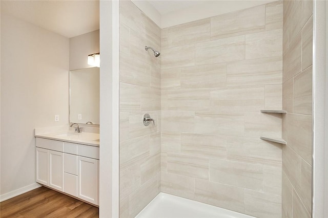 bathroom with hardwood / wood-style floors, vanity, and a tile shower