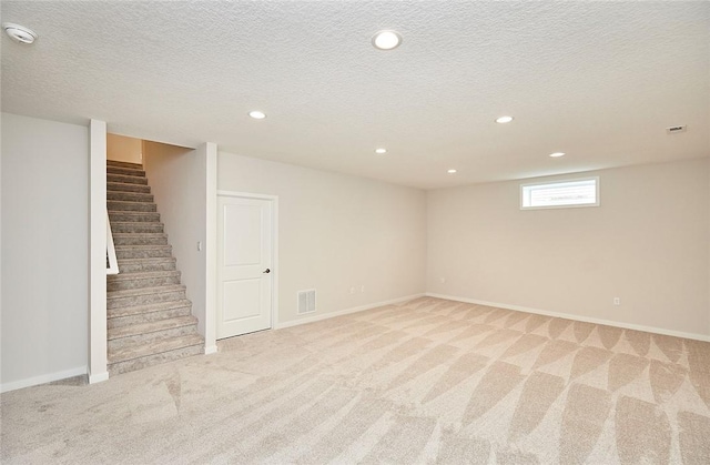 basement with a textured ceiling and light colored carpet