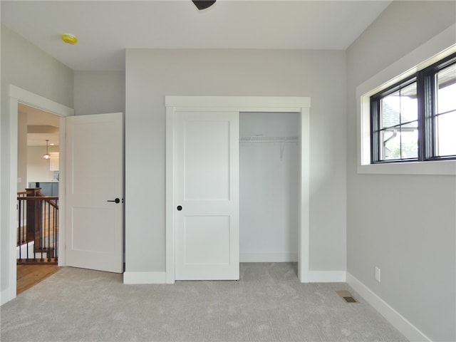 unfurnished bedroom with a closet and light carpet